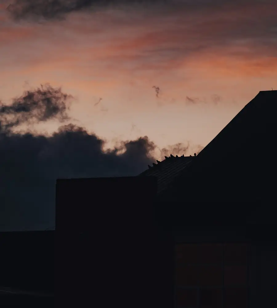 House roofline silhouetted against a dusk sky