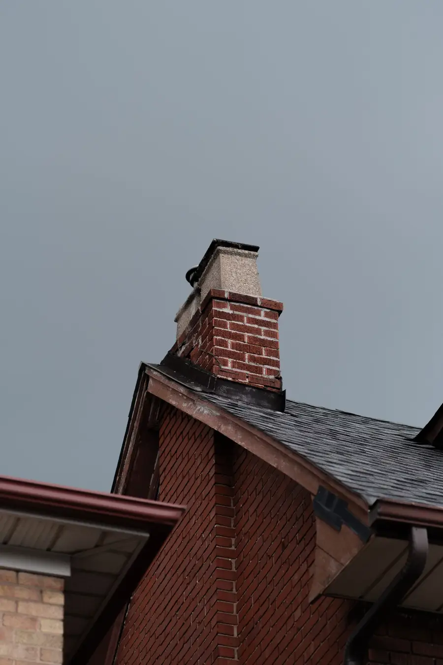 The soffit and fascia junction where a roof meets a brick wall, seen from below